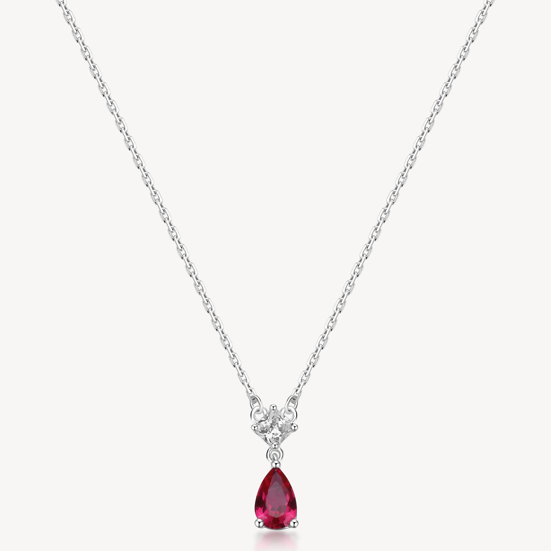 Collana girocollo in argento rodiato 925‰ e pendente con square cubic zirconia e pear cubic zirconia colore ruby. Lunghezza collana 44cm.
